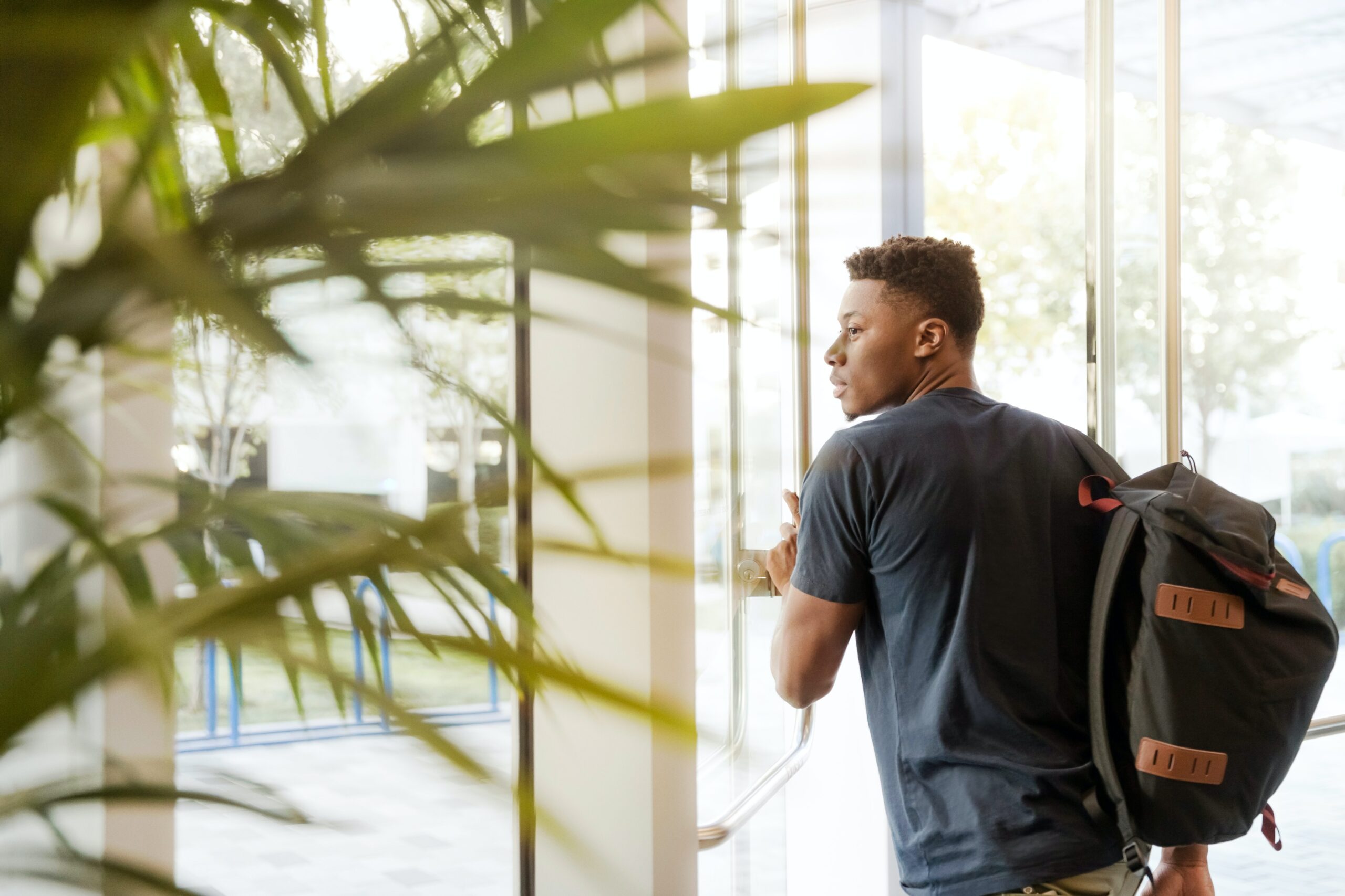 A photo of a male student wearing a backpack, leaving campus.