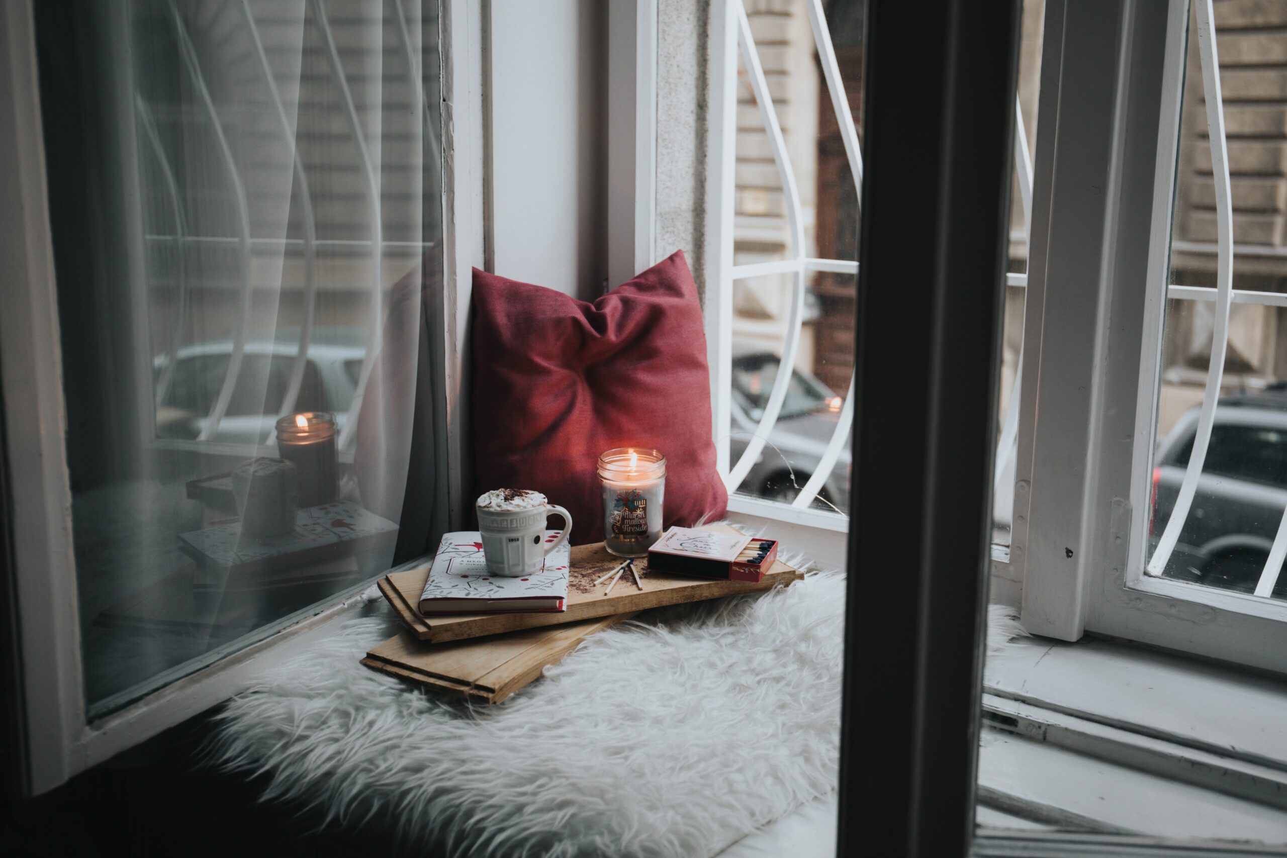 a pillow, books, and a candle in a comfy corner